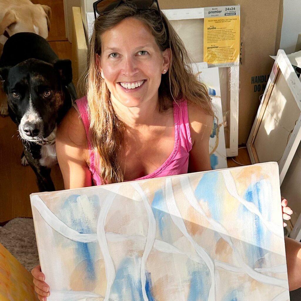 Meg holding a painting, and her dog